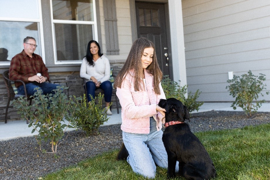 Girl petting her dog in front of their new home