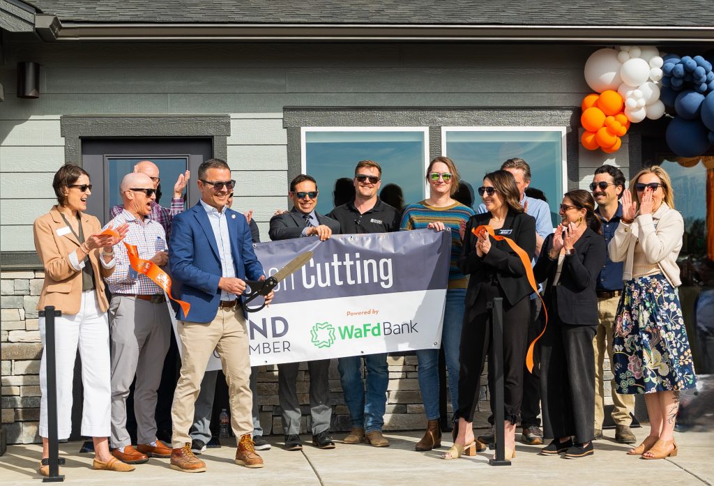 Oregon State Senator Anthony Broadman cuts the ribbon at the Hayden Homes Parkside Place model home grand opening in Bend, surrounded by Hayden Homes team members and Bend Chamber of Commerce leaders